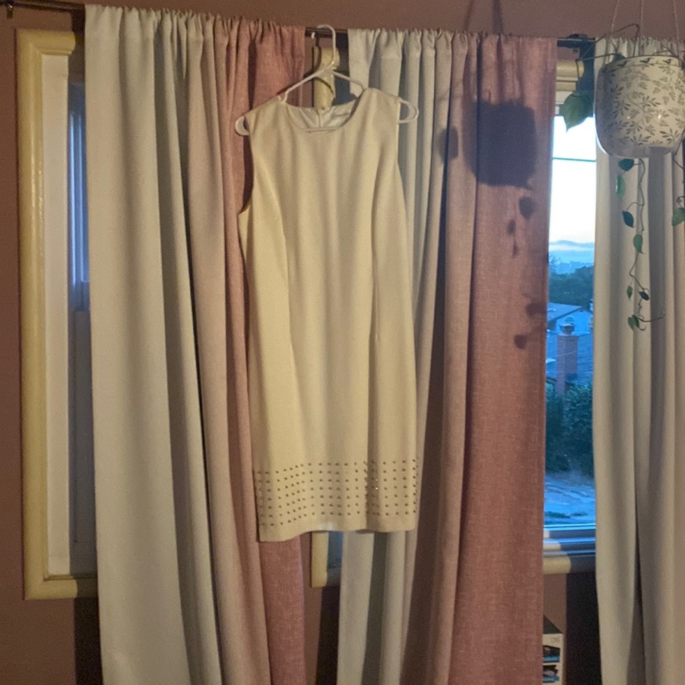 White Calvin klein dress with gold studs on bottom.